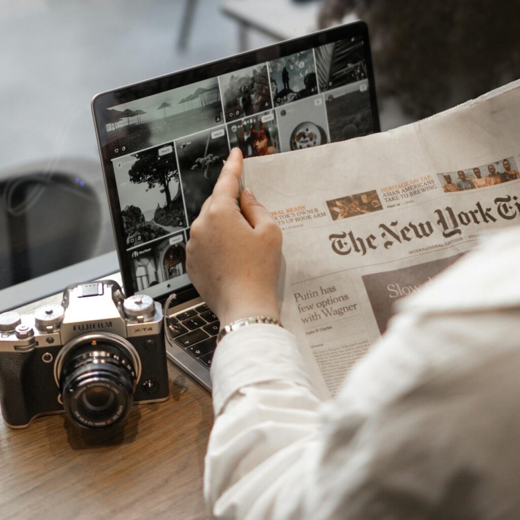 Mastering the First Impression: Your intriguing post title goes here Close-up of a person reading The New York Times by a laptop and camera.