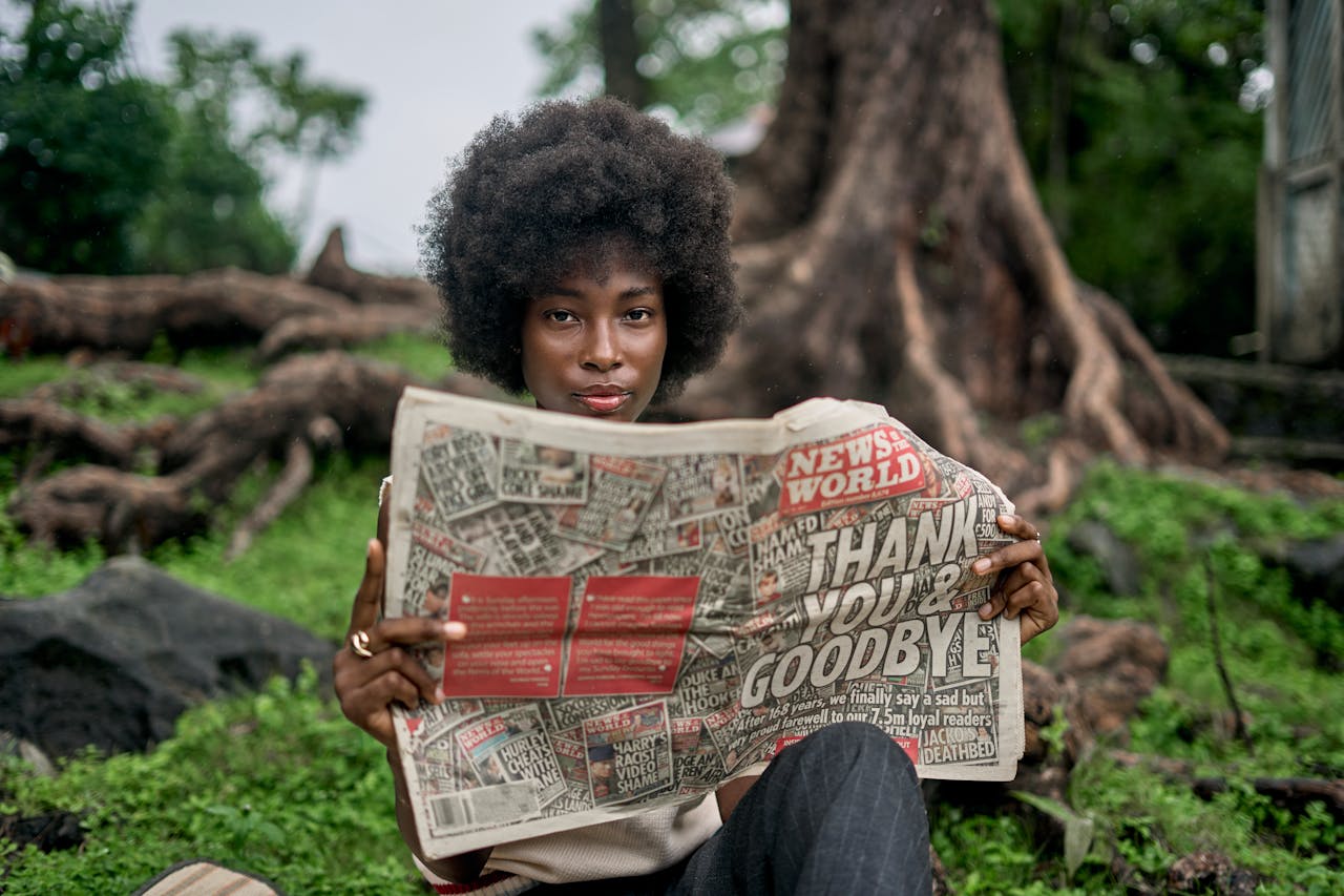A woman enjoys reading a newspaper in a natural outdoor setting, showcasing leisure and nature.